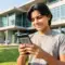 Estudante confere informações sobre o local de prova do Enem 2026 pelo celular em ambiente externo.